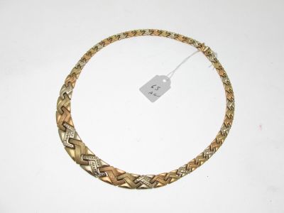 une photo d'un collier en or posé sur une table blanche
