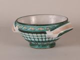 a green and white bowl with a handle on a table