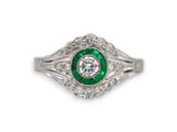 gros plan d'une bague en diamant et émeraude sur fond blanc