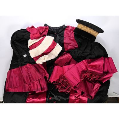 une robe noire et rouge surmontée d'un chapeau
