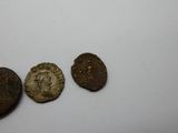 Trois pièces de monnaie romaines antiques sont représentées sur un fond blanc