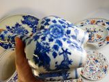 a person holding a blue and white teapot in their hand