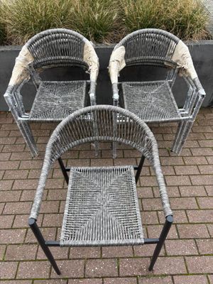 deux chaises et une table sur une terrasse en briques, à côté d'une jardinière