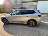 the bmw x1 is parked in front of a garage