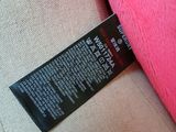 the label on the back of a pink teddy bear sitting on top of a couch