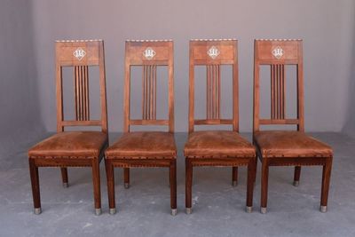 quatre chaises en bois avec des assises recouvertes de cuir dans une pièce