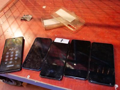 several cell phones are lined up on a table next to a remote control