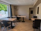 des tables et des chaises dans une pièce dotée d'une grande fenêtre donnant sur l'extérieur