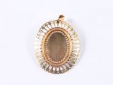 a close up of a gold and silver pendant on a white surface
