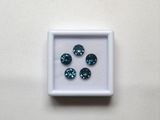 quatre diamants bleus dans une boîte blanche posée sur une surface blanche