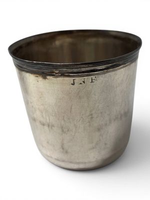 a silver cup that is sitting on a white surface