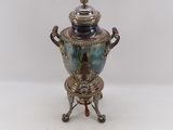 a silver and blue vase on a stand on a white surface