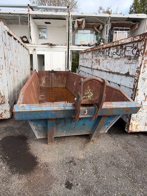une benne à ordures rouillée abandonnée sur un parking