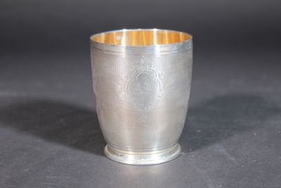 an old silver cup sitting on top of a table next to a black background