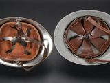 pair of helmets with leather covers on them sitting on a table