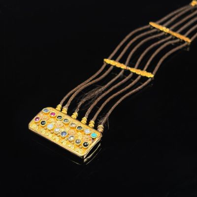 a gold necklace with multi colored stones on a black background