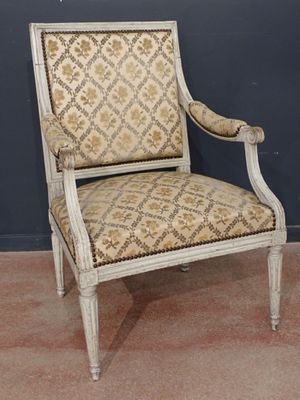 an old chair with a patterned upholstered back and arms