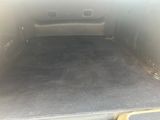 l'arrière d'une voiture dont le coffre est ouvert et dont le plancher est recouvert de moquette