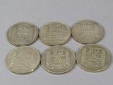 six different coins are shown on a table with a white background