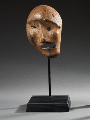 un masque en bois posé sur un socle à base noire
