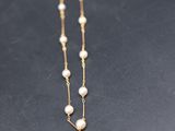 a gold necklace with pearls on a black surface