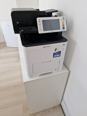 une imprimante blanche posée sur une pile de cartons blancs