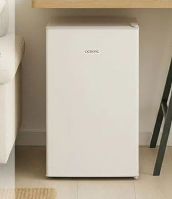 a small white refrigerator in the corner of a living room