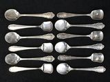 six silver spoons are arranged in a row on a black surface