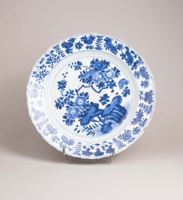 assiette bleue et blanche ornée de fleurs, posée sur un socle