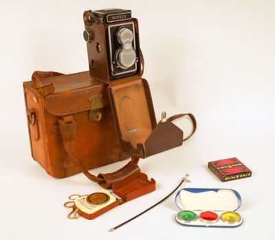 un vieil appareil photo et quelques autres objets posés sur une surface blanche