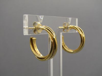 un gros plan sur une paire de boucles d'oreilles créoles en or posées sur un présentoir transparent
