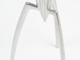 a close up of a metal juicer on a white surface