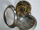 une petite montre de poche en argent avec une horloge à l'intérieur