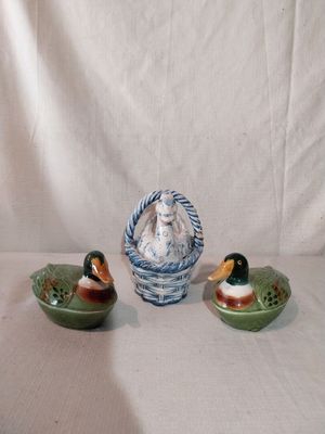 trois canards en céramique posés sur une table, à côté d'un panier