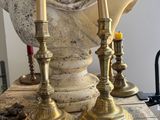 two candles that are sitting on a table next to a bust