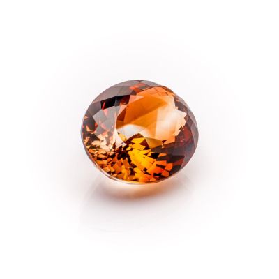 a close up view of a faceted orange sapphire stone on a white surface