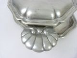 two silver dishes on a white table with a white background