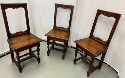 trois chaises anciennes en bois sont alignées devant un fond blanc