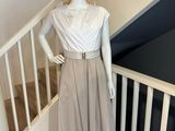 mannequin vêtu d'une robe beige et d'un chapeau de paille, debout sur un escalier