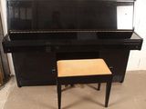 a black piano with a stool in front of it