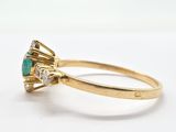 a close up of a gold ring with an emerald and diamond