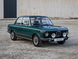une voiture verte garée devant un immeuble