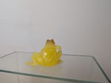 a small yellow frog sitting on top of a glass table