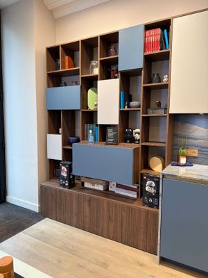 a room with a table, bookshelf, and a refrigerator in it