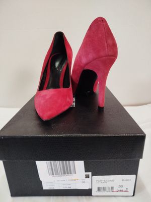 des chaussures à talons hauts roses posées sur une boîte noire, elle-même posée sur une surface blanche