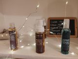 three bottles of essential oils on a shelf with fairy lights