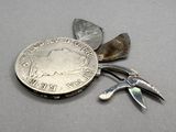 a silver coin with a pair of pliers next to it
