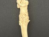 an ivory figurine of a man holding a bird on a black surface