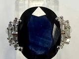 gros plan d'une bague avec une pierre bleue entourée de diamants
