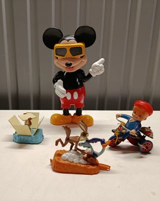 Des figurines de Mickey Mouse sont posées sur une table à côté d'un bateau miniature